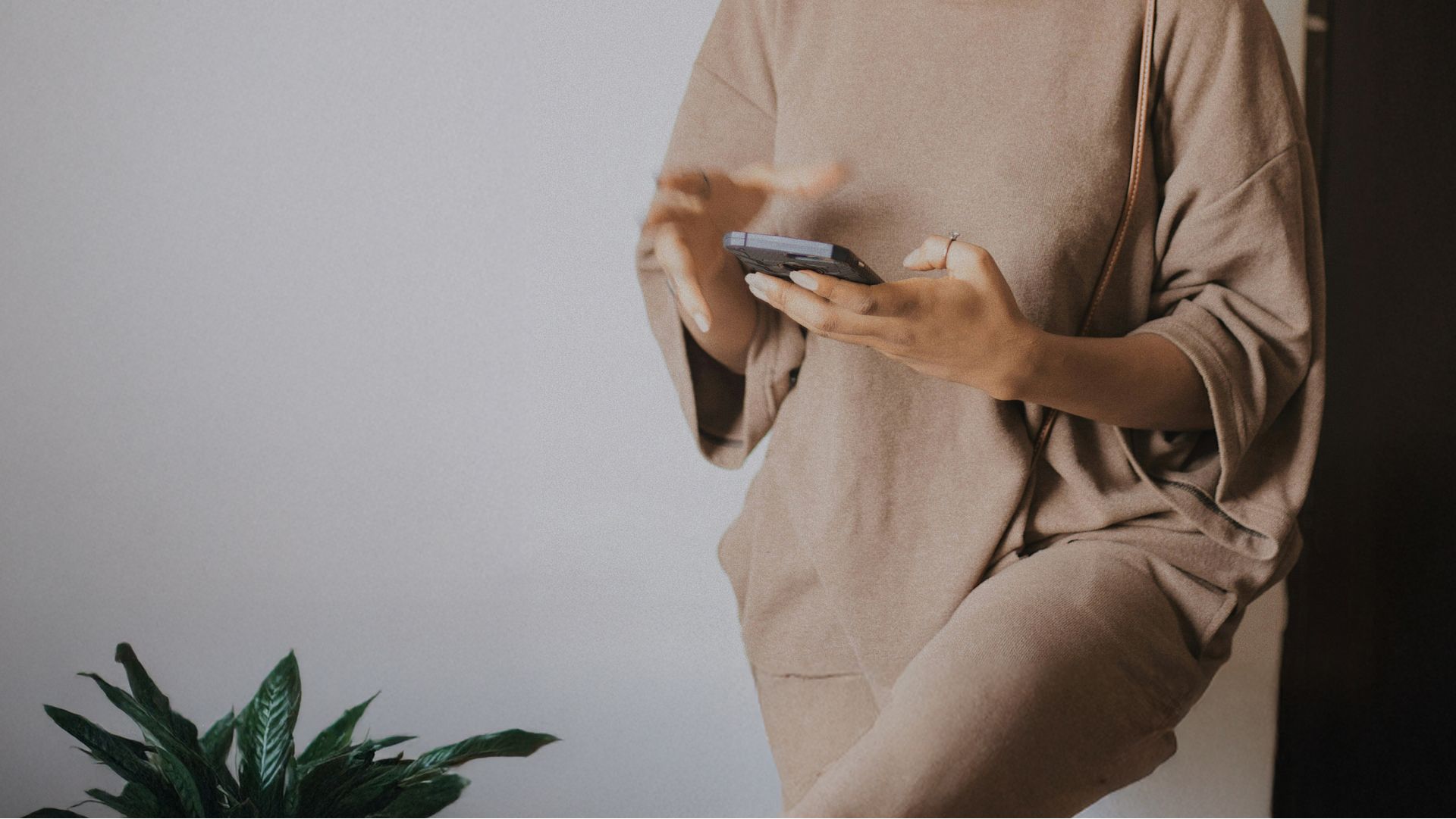 An image of someone leaning against the wall in their home while using the Aster AI app on their smartphone.