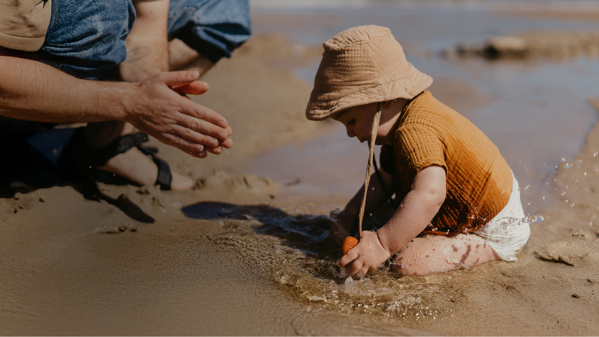 An image of a parent playing with their toddler on the beach.